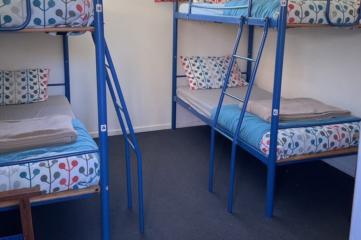 A room with three bunk beds, each with patterned bedding and pillows.