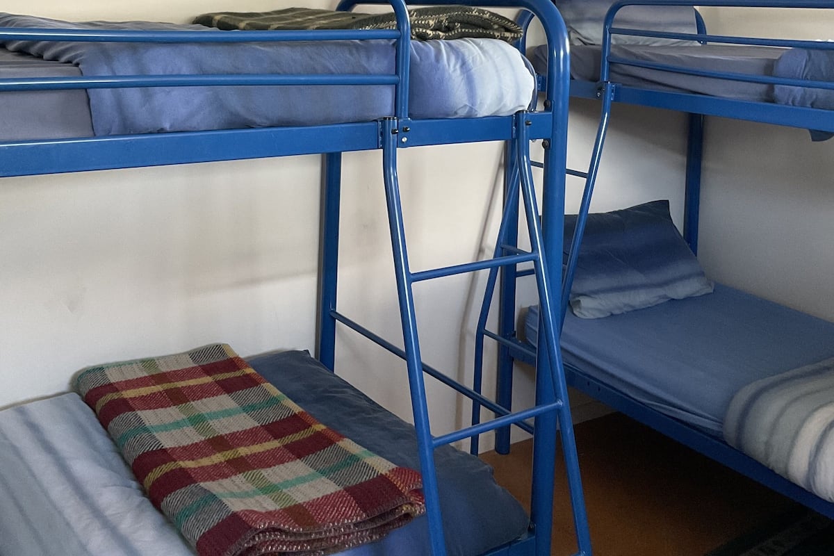 A bunk bed room with blue metal frames and white walls.