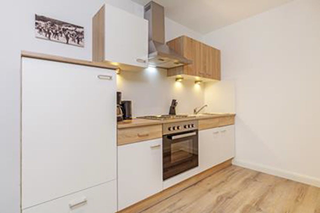 A modern kitchen with white cabinetry, a built-in oven, and a wooden countertop.