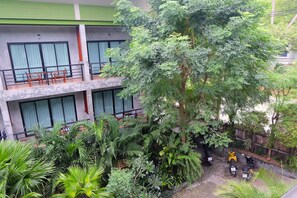 Un edifici de diverses plantes amb balcons, vegetació abundant i patinets estacionats.