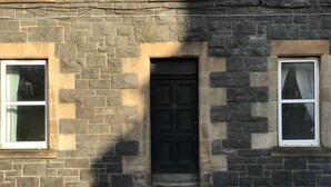 Un bâtiment en pierre avec une porte noire, deux fenêtres et le numéro « 37 » bien visible sur la porte.