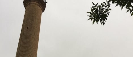 A tall brick minaret with a dome at the top, surrounded by arched windows.