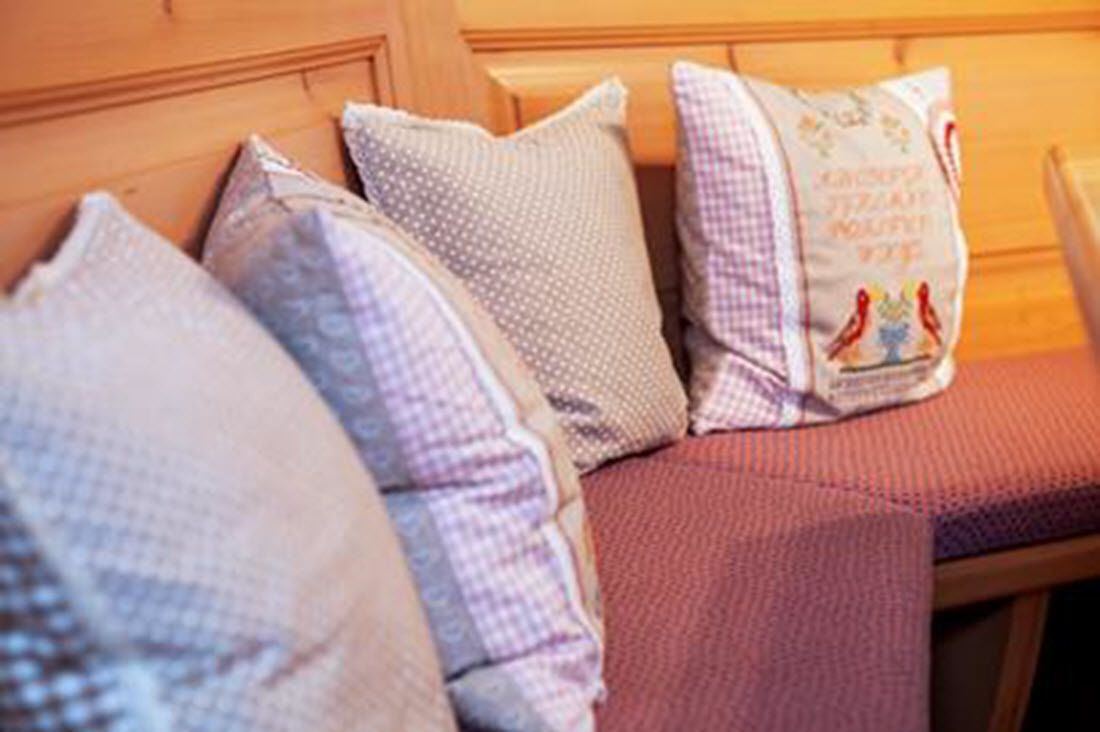A wooden headboard with a cushioned bench and decorative pillows.