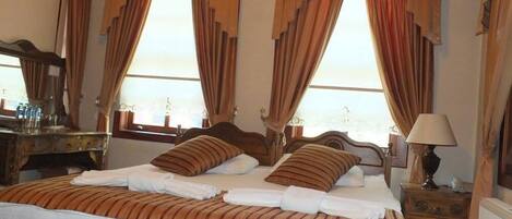 A hotel room with a large bed, two pillows, a nightstand with a lamp, and a dresser.