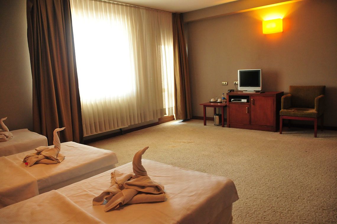 A hotel room with two beds, a television, a chair, and a lamp.