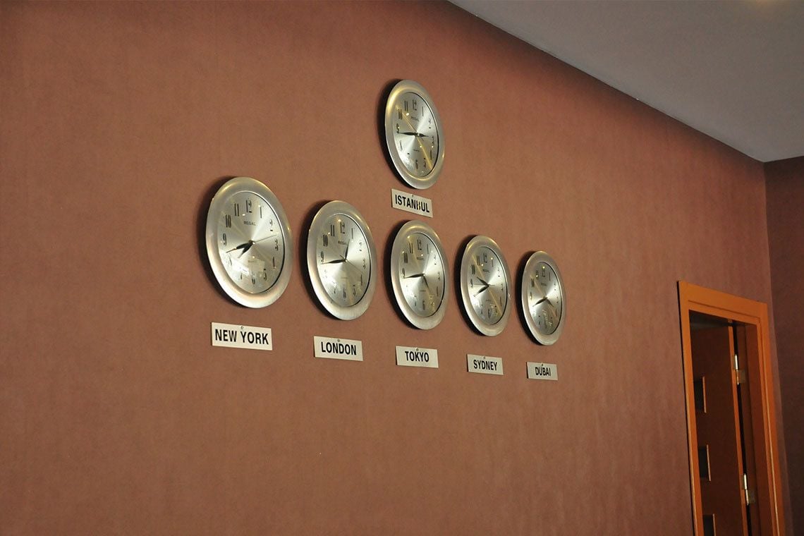 Paret amb rellotges indicant l'hora de diferents ciutats, identificades amb els seus noms.