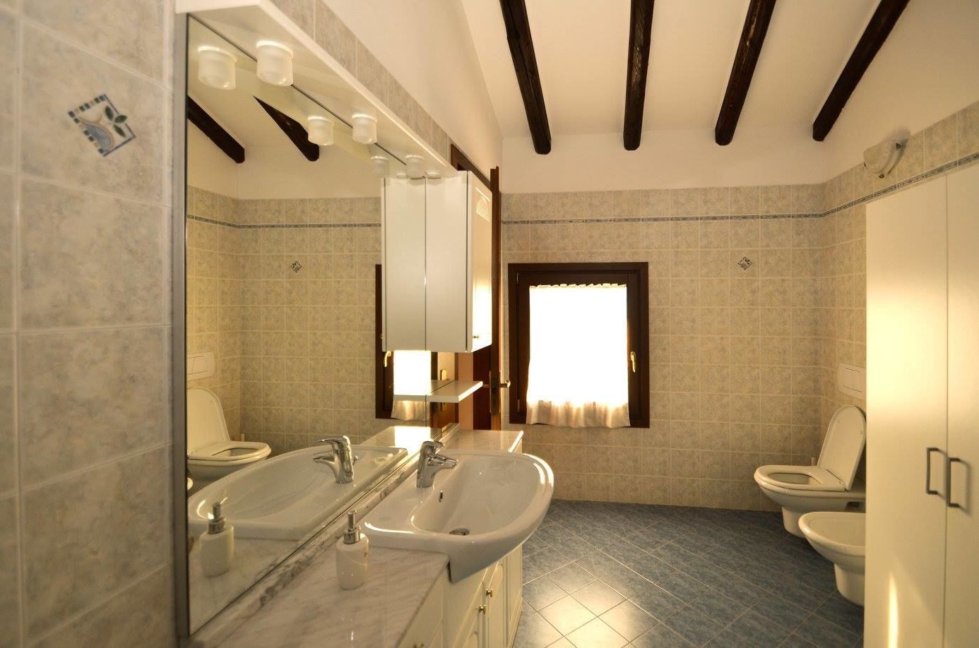A bathroom with two sinks, a large mirror, and a toilet.
