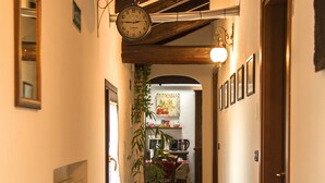 A hallway with wooden flooring, a hanging wall clock, a potted plant, and a radiator. - Chiaro Di Luna (San Vito al Tagliamento)