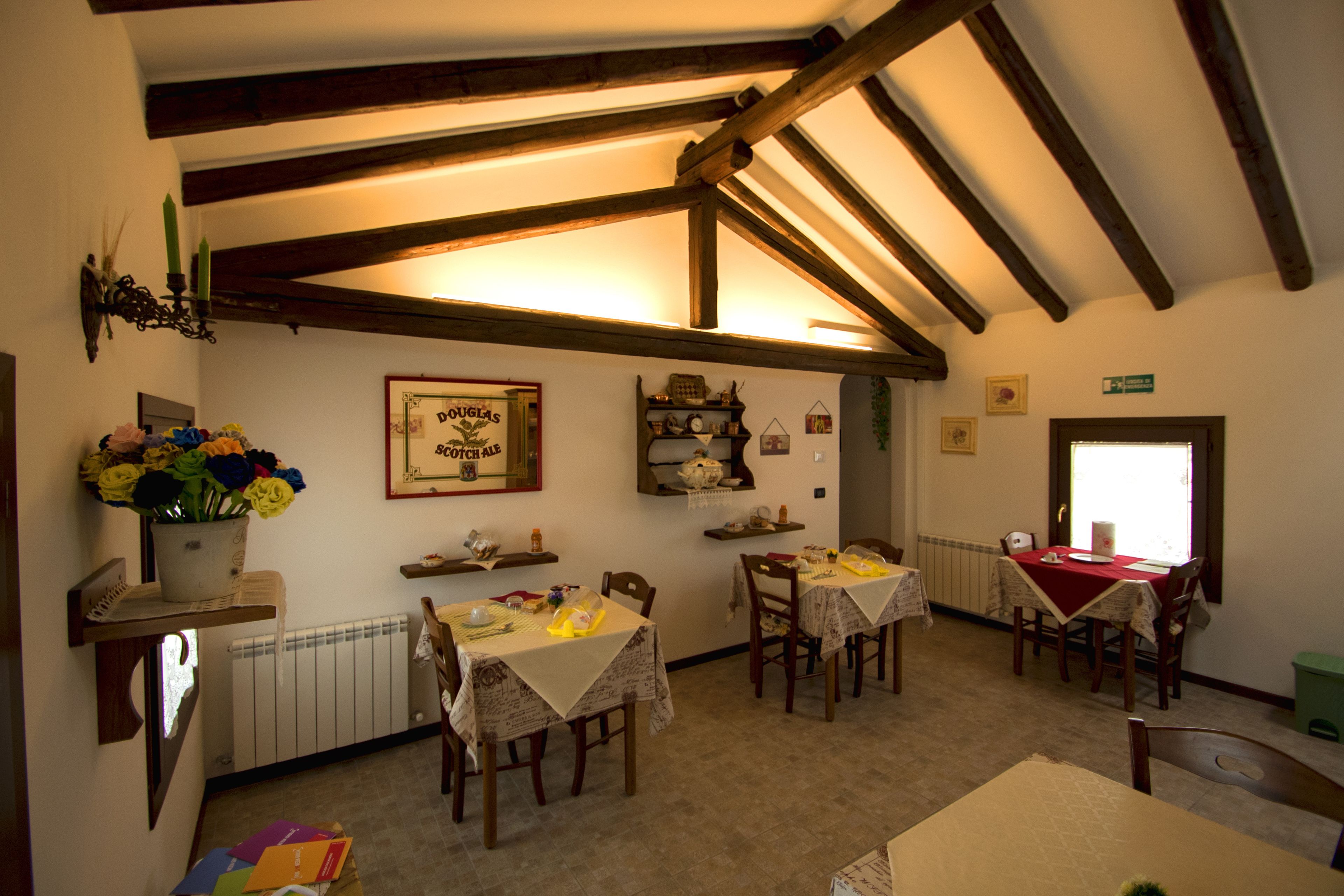 A dining area with wooden beams, tables with tablecloths, and a radiator.