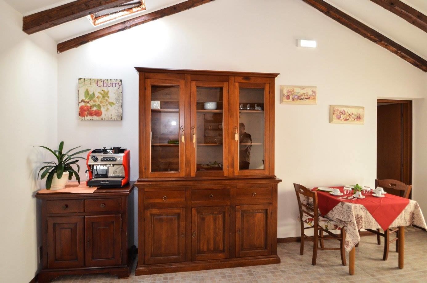 Un comedor con un armario de madera, una mesa dispuesta para dos personas y una cafetera.