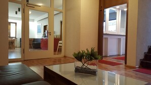 A modern living room with a glass coffee table, a sofa, and a plant. - Gästehaus Ruh (Freiburg im Breisgau)