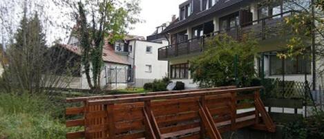 A residential building with a balcony, a small garden, and a wooden fence.