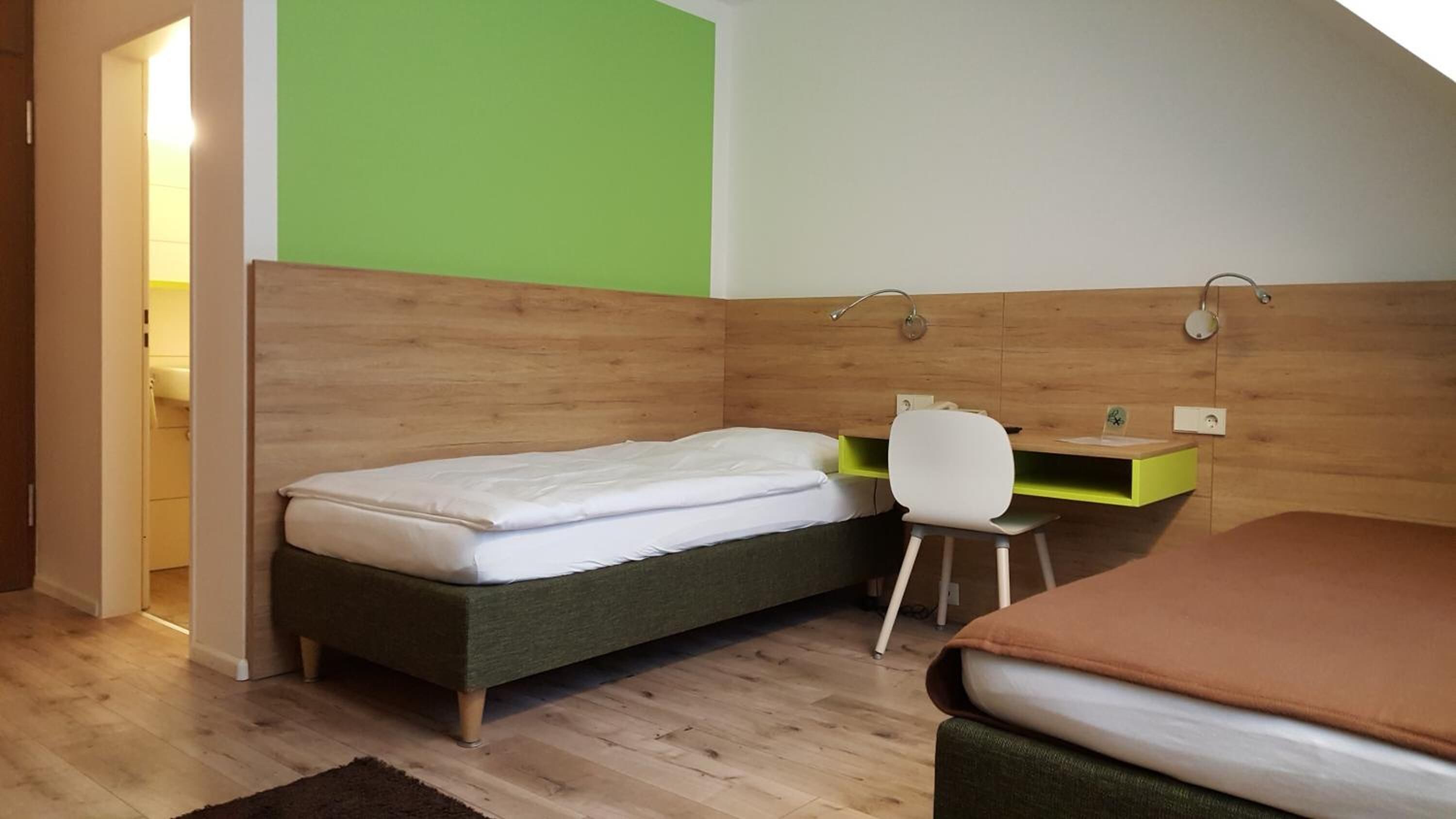 Una habitación pequeña y funcional con cama, escritorio y silla.