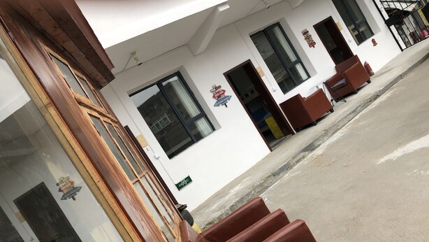 Un edificio con fachada blanca, ventanas grandes y un extintor en la pared.
