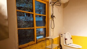 Un baño con ventana, lavamanos, inodoro y ducha.
