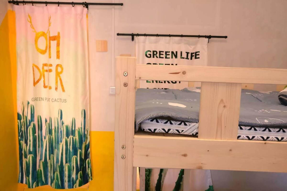 Uma cama beliche com cortina em tons de verde e um letreiro que diz "GREEN LIFE GREEN".