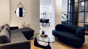Una sala moderna con un sofá modular, una mesa de centro de vidrio y vista al comedor.