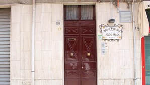 Uma porta dupla fechada com padrões geométricos, uma placa com a inscrição "Bld & Broked Party's House" e o número "16" na parede.