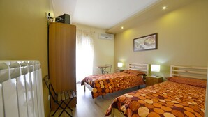 Quarto com duas camas, um radiador, uma escrivaninha e uma cadeira.