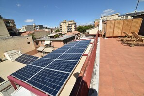 A rooftop with solar panels, a red railing, and a view of surrounding buildings. - B&B Patty's House (Adrano)
