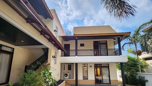 Una casa de dos pisos con piscina, un balcón y una escalera que lleva al nivel superior.