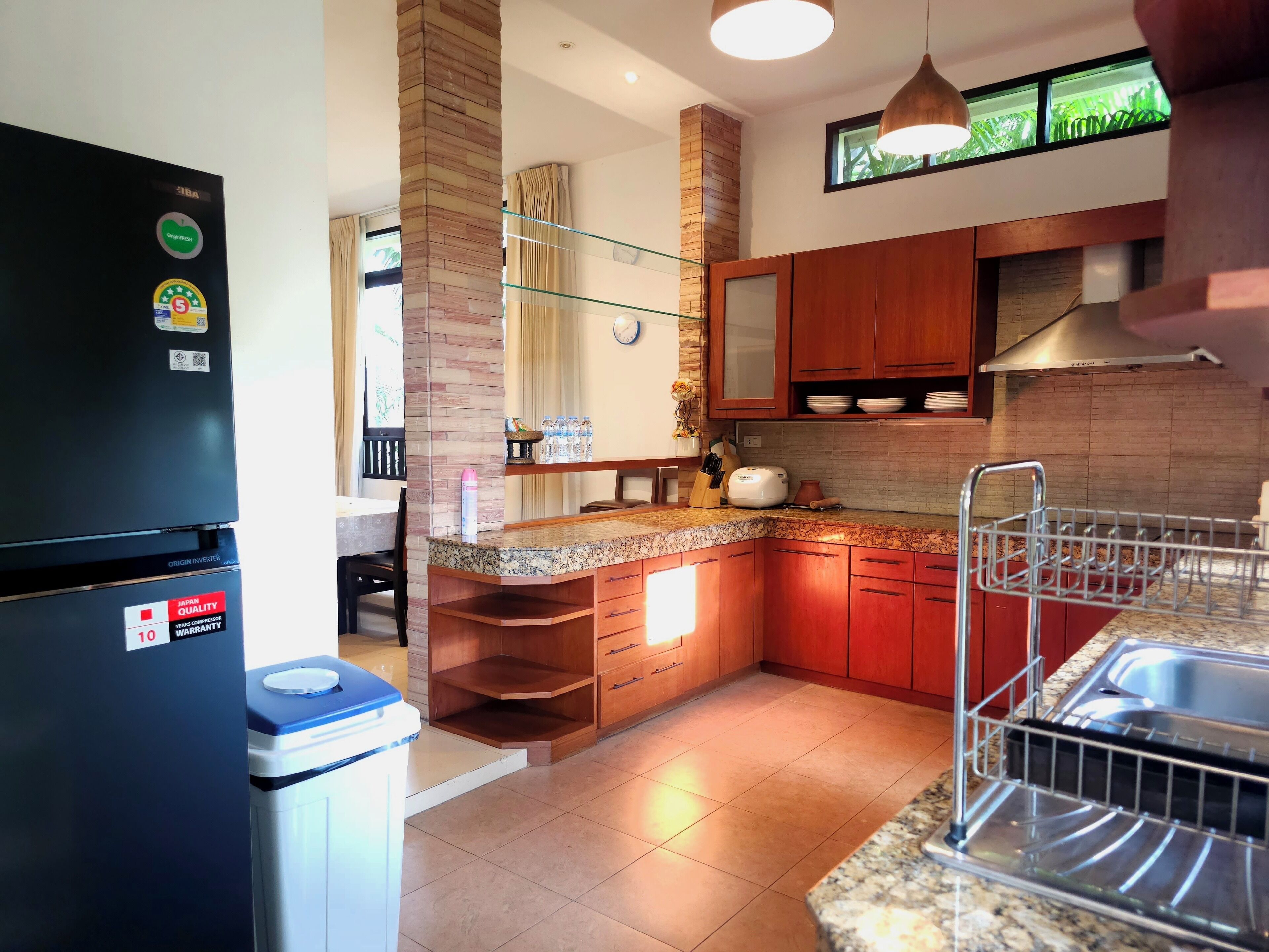 A modern kitchen with a built-in refrigerator, wooden cabinets, granite countertops, and a stainless steel sink.