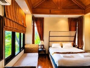 Habitación de hotel con una cama grande, una mesita de noche, una silla y una ventana con cortinas.