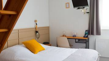 A hotel room with a bed, a desk, a chair, a television, and a window with curtains.