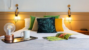 A neatly made bed with a lamp, a mug, and a magazine on a tray. - Tourhotel (Béthune)