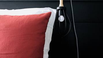 A bed with a red pillow, a black and white checkered blanket, and a wooden nightstand.