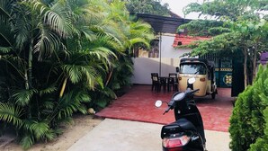 A motorbike parked in front of a building with a red carpet, surrounded by lush greenery. - Yarl Crown Inn (Kandy)