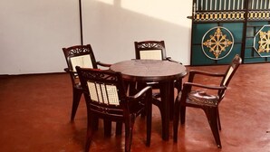 A round wooden table with four chairs, each with a woven backrest. - Yarl Crown Inn (Kandy)