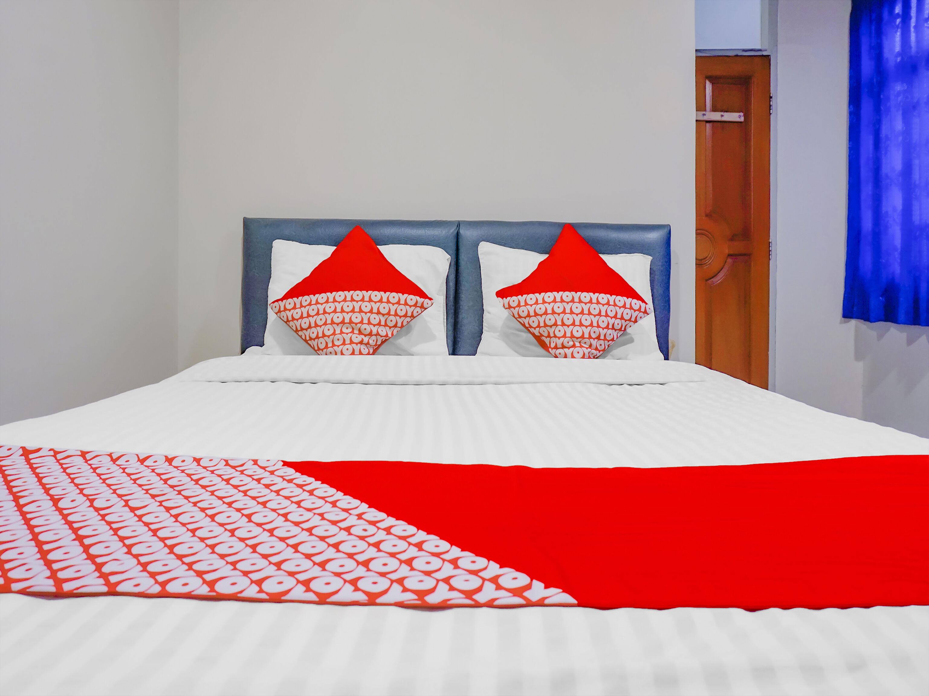 A bed with white bedding and red accents, including pillows and a blanket.