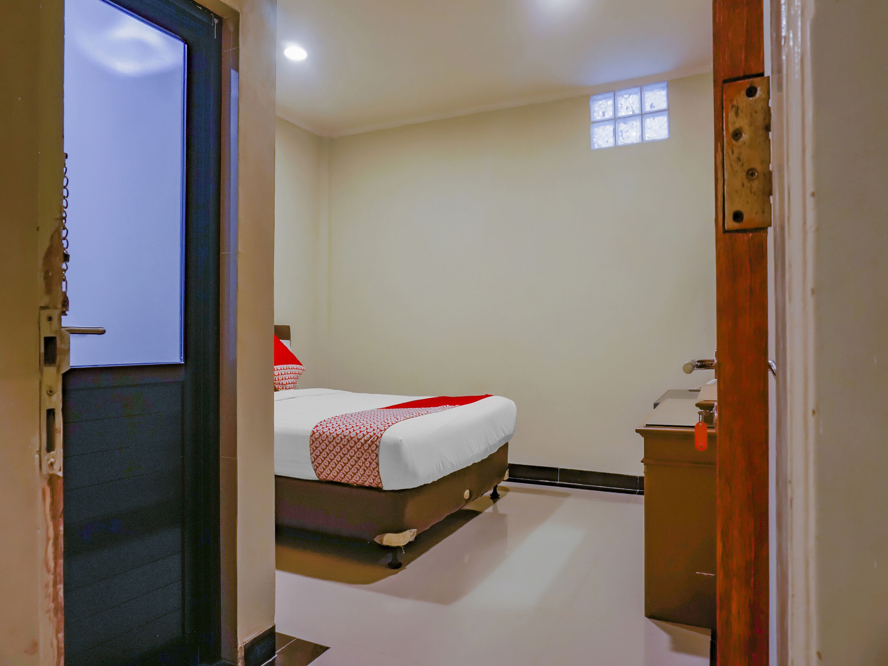 A hotel room with a bed, a small bedside table, and a window.