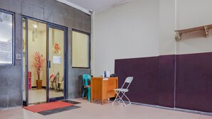A reception area with a desk, chairs, a potted plant, and a red mat. - OYO 117 Blueberry Homestay (Jakarta)