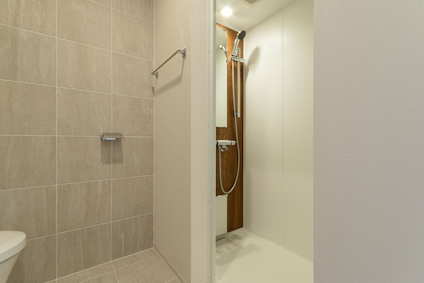 Un baño moderno con ducha, inodoro y puerta de madera.