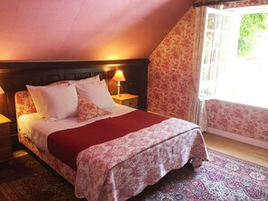 A bedroom with a bed, nightstands, a lamp, floral wallpaper, and a window with curtains. - La Croix du Reh (Châteauneuf-la-Forêt)
