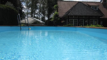 Una piscina al aire libre de temporada, sillones reclinables de piscina