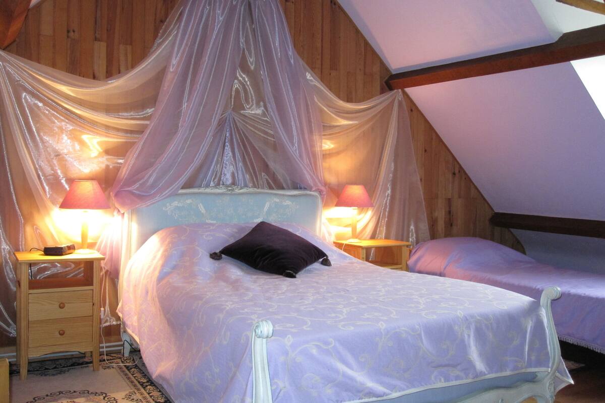 A bedroom with a canopy bed, two bedside lamps, and a wooden ceiling.