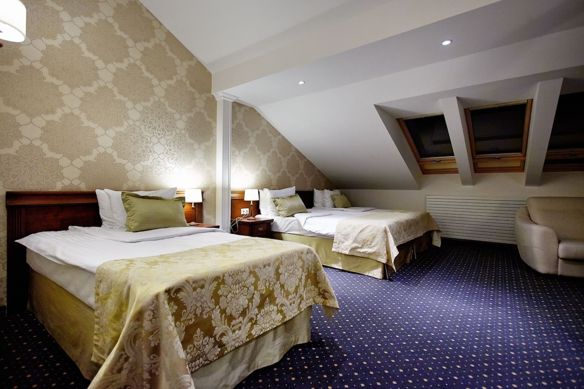 Hotellihuone, jossa on kaksi sänkyä, suuri ikkuna ja katossa oleva kattovalokuvio.