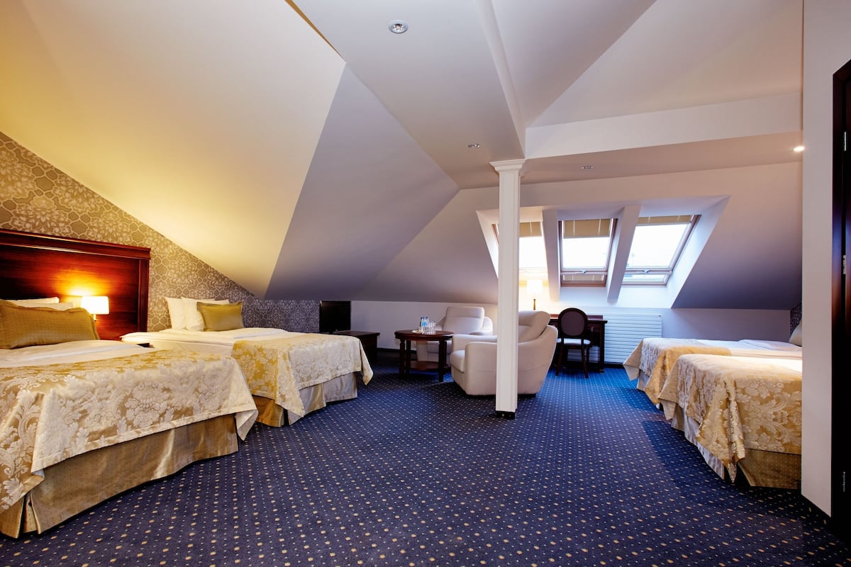 Hotellihuone, jossa on kaksi sänkyä, työpöytä, tuoli ja suuri ikkuna.