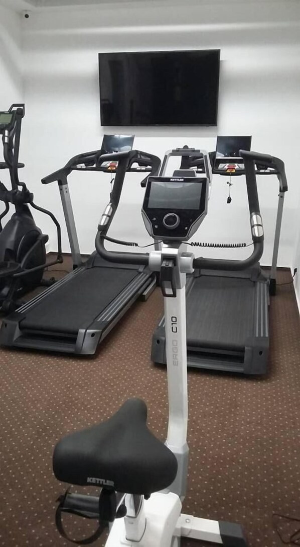 A home gym with two treadmills, one elliptical, and a stationary bike.