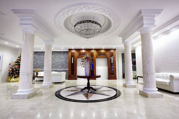 A lobby with marble columns, a central round table, and a chandelier.