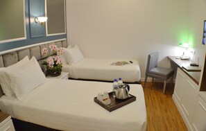A hotel room with two beds, a desk with a chair, a small table with a tray of toiletries, and a wall-mounted lamp. - H Boutique Hotel Sri Petaling (Kuala Lumpur)
