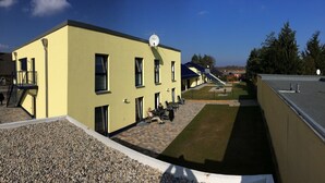 A yellow building with a satellite dish, outdoor seating, and a playground. - Bett & Bike Eden (Senftenberg)