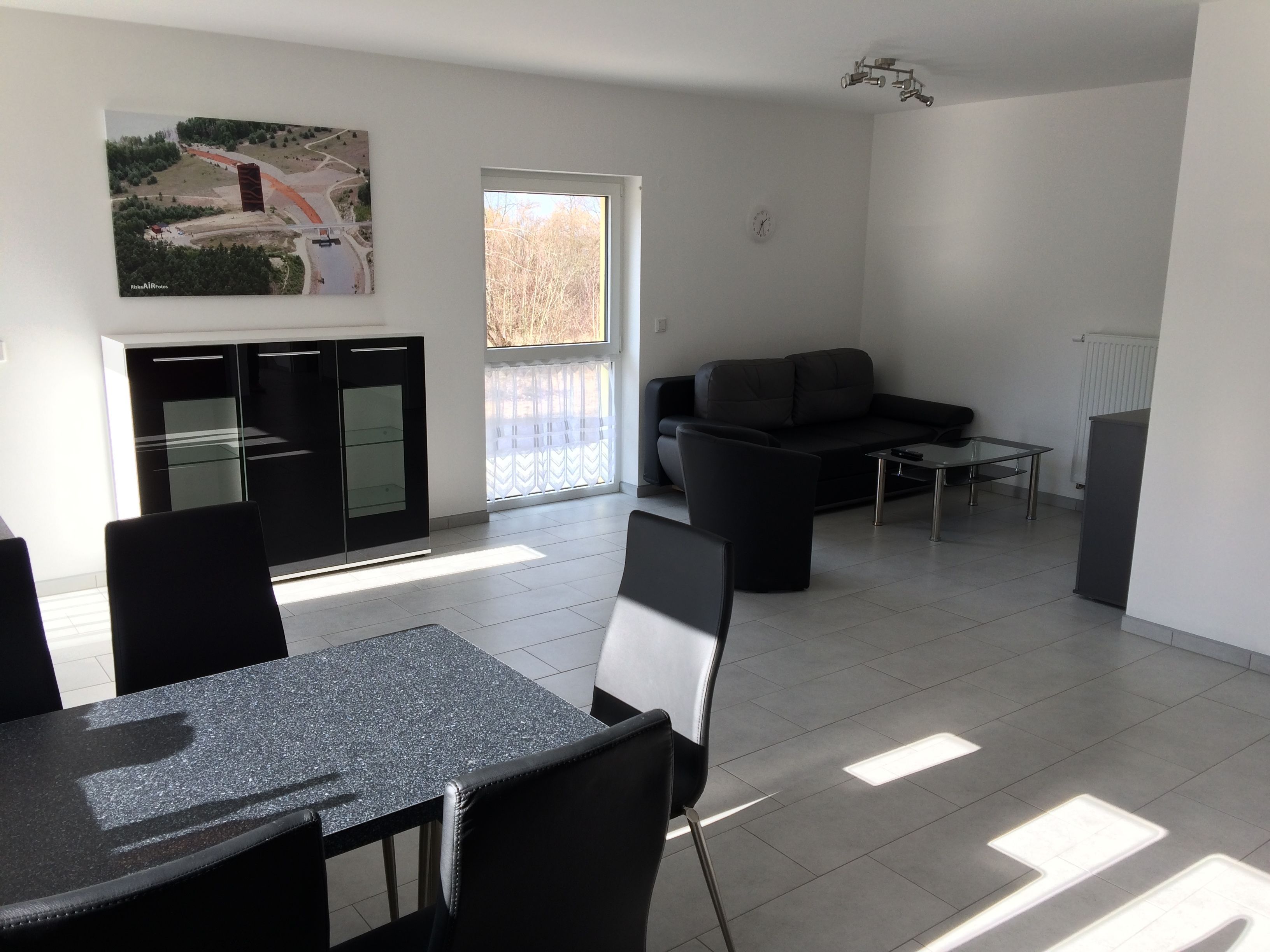 Una sala de estar moderna con un sofá, una mesa de comedor con sillas y una zona de cocina con un mueble.
