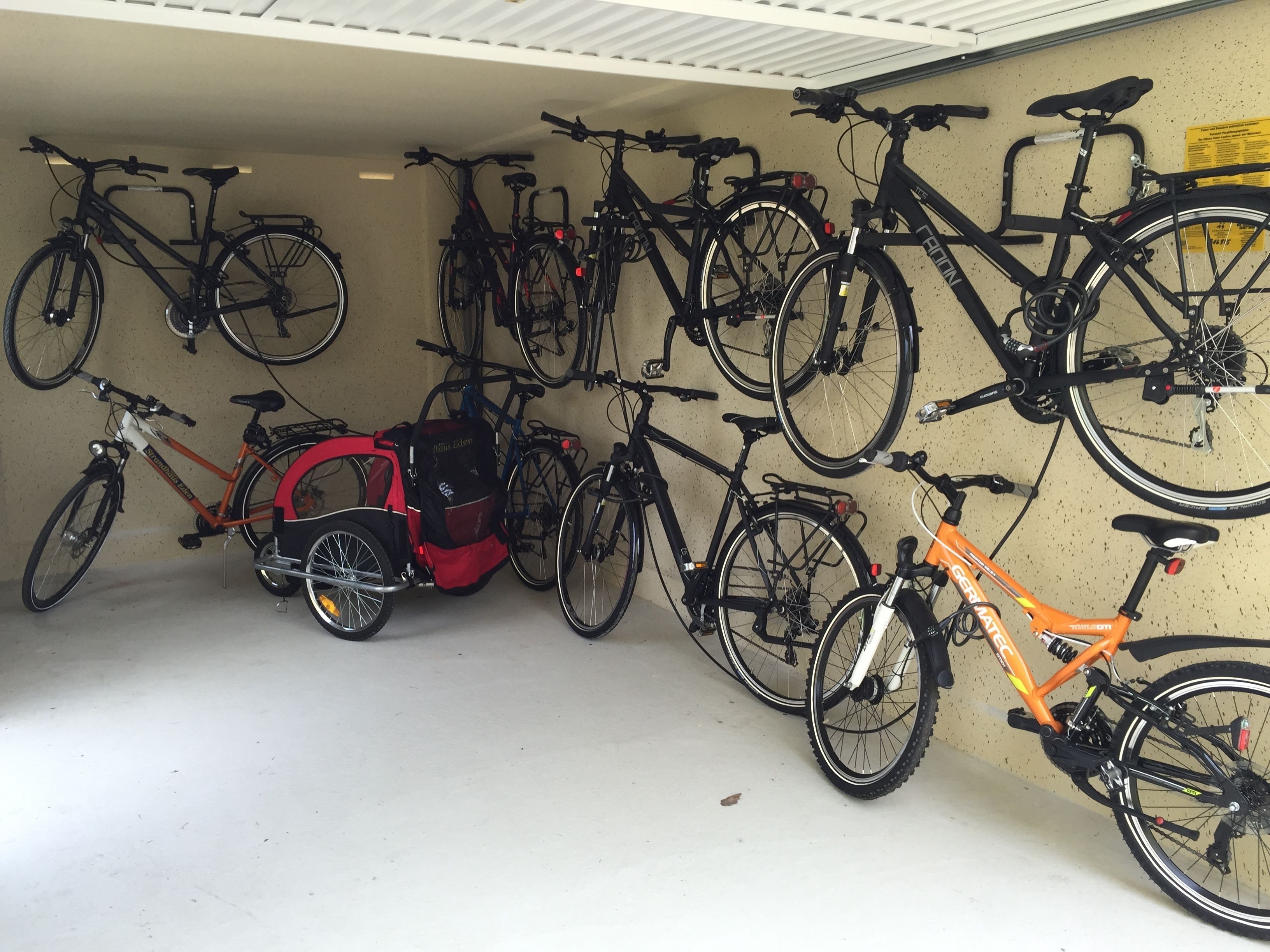 A bicycle storage area with multiple bicycles and a red child bike carrier.