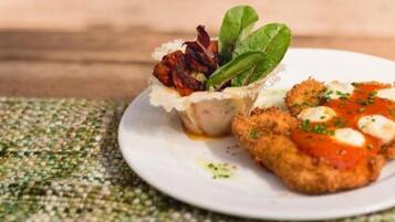 A plate with a breaded cutlet, a small cup of sauce, and a garnish of greens.