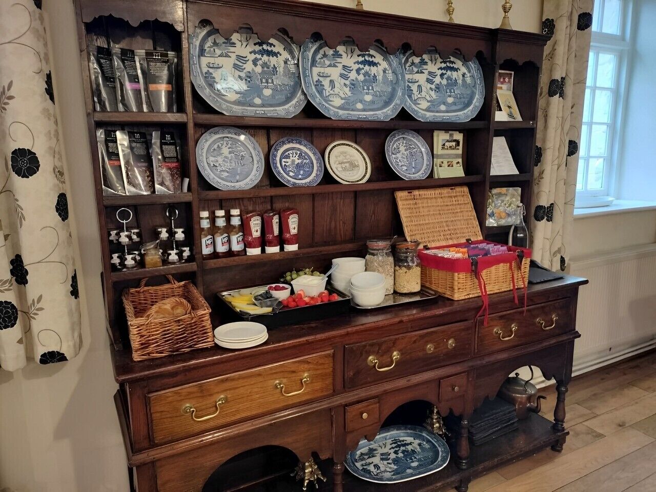 Un mueble de madera con estantes que exhiben platos de cerámica, frascos y utensilios de cocina.