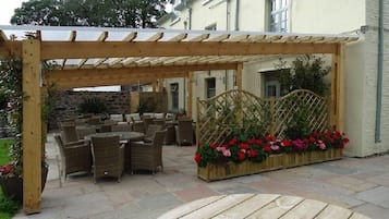 Un patio al aire libre con mobiliario de mimbre y una pérgola de madera.